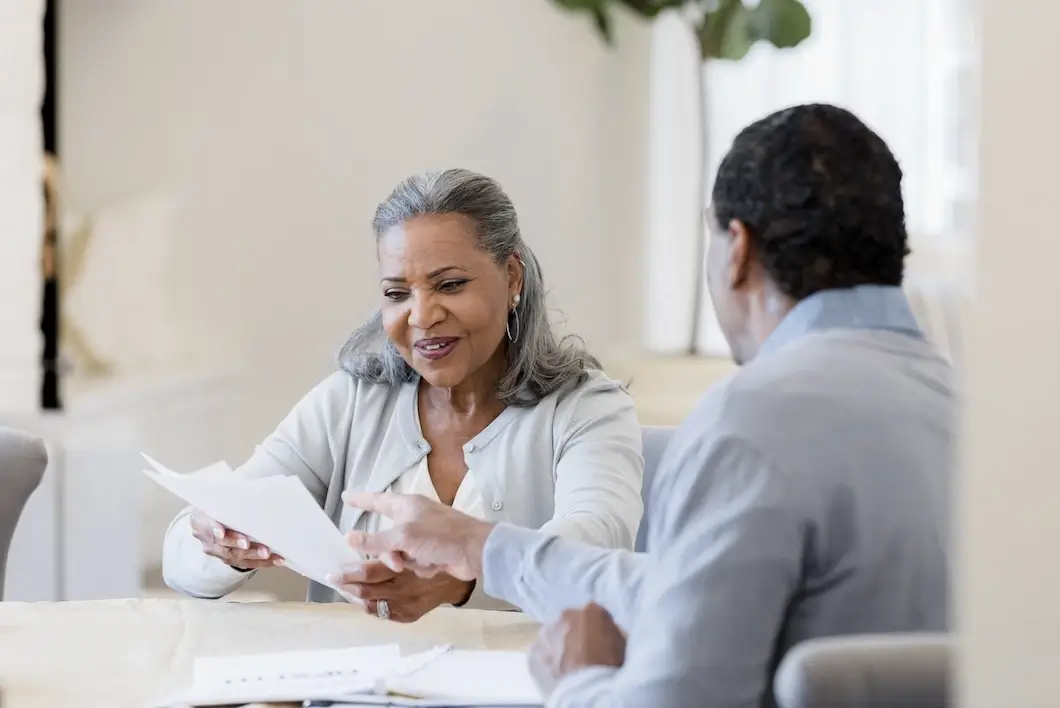 Senior woman smiles as male insurance agent explains paperwork